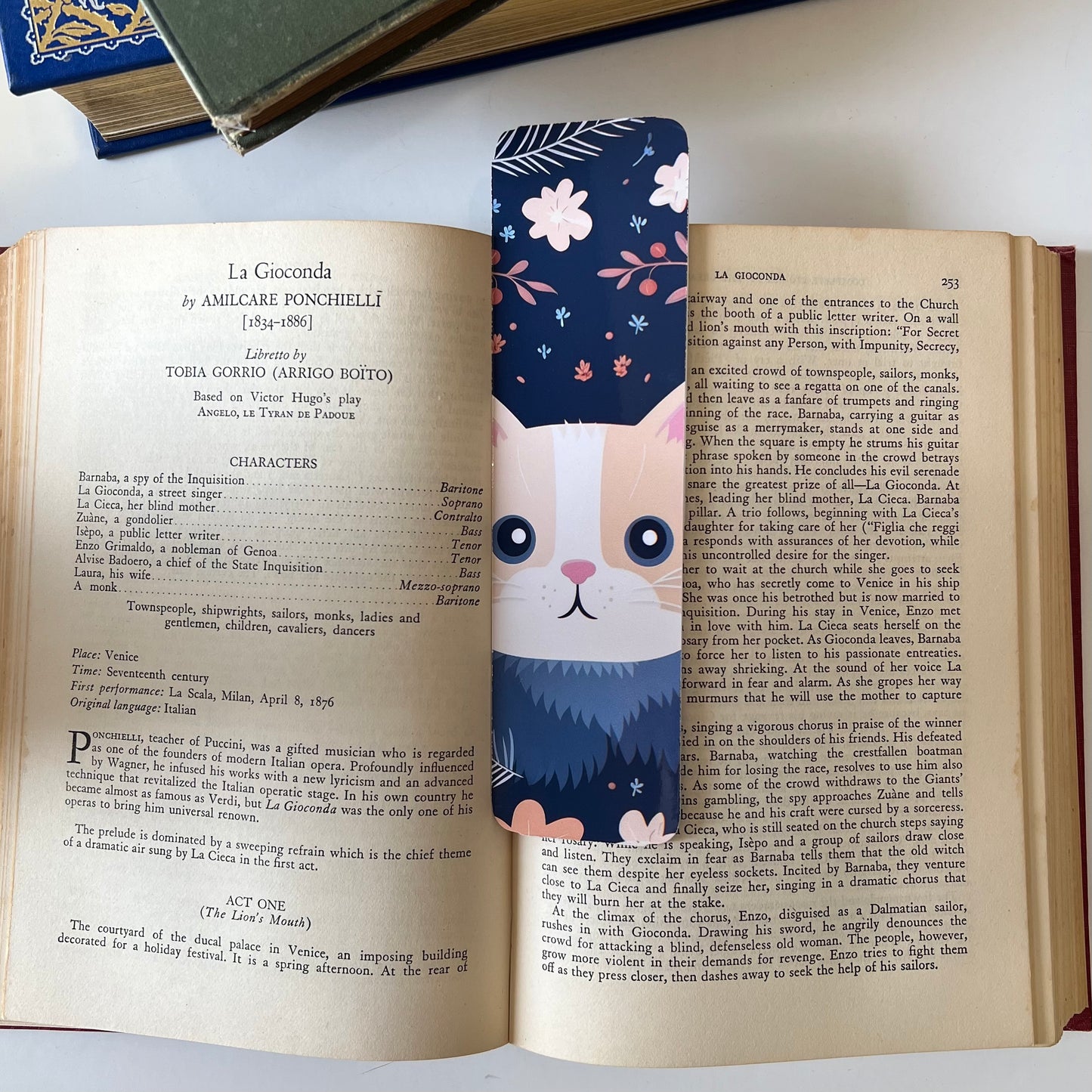 A handmade rectangular glossy bookmark with cute cat faces and floral patterns on a navy background.
