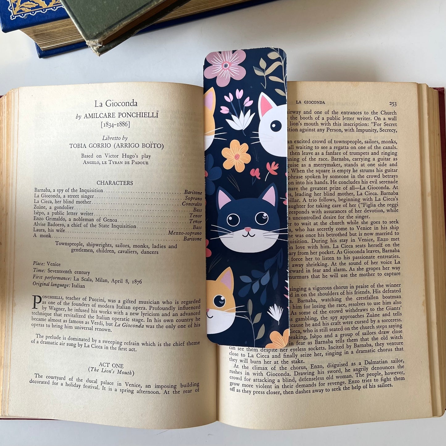 A handmade rectangular glossy bookmark with cute cat faces and floral patterns on a navy background.