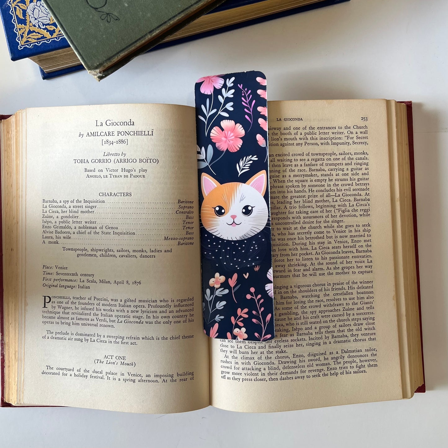 A handmade rectangular glossy bookmark with cute cat faces and floral patterns on a navy background.
