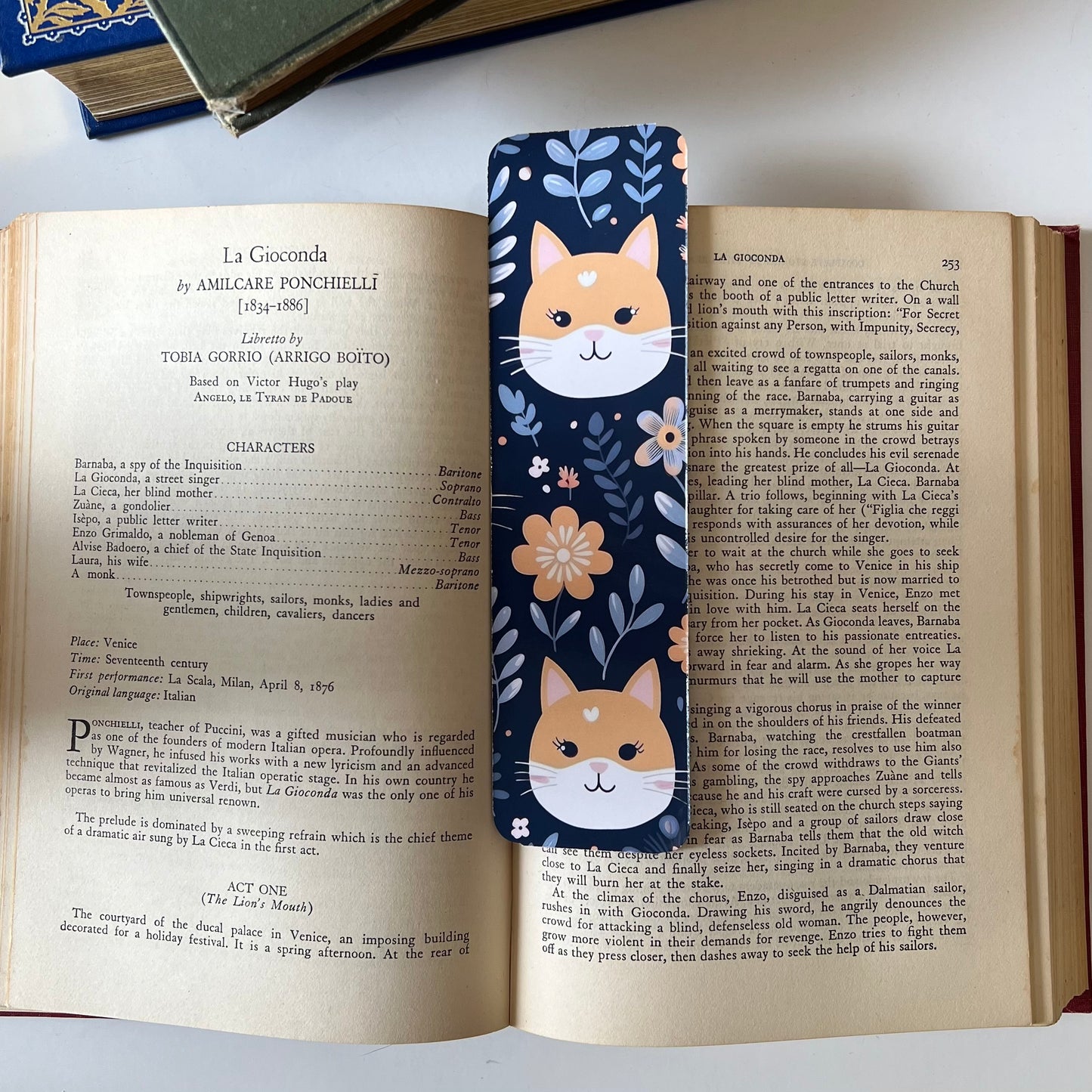 A handmade rectangular glossy bookmark with cute cat faces and floral patterns on a navy background.