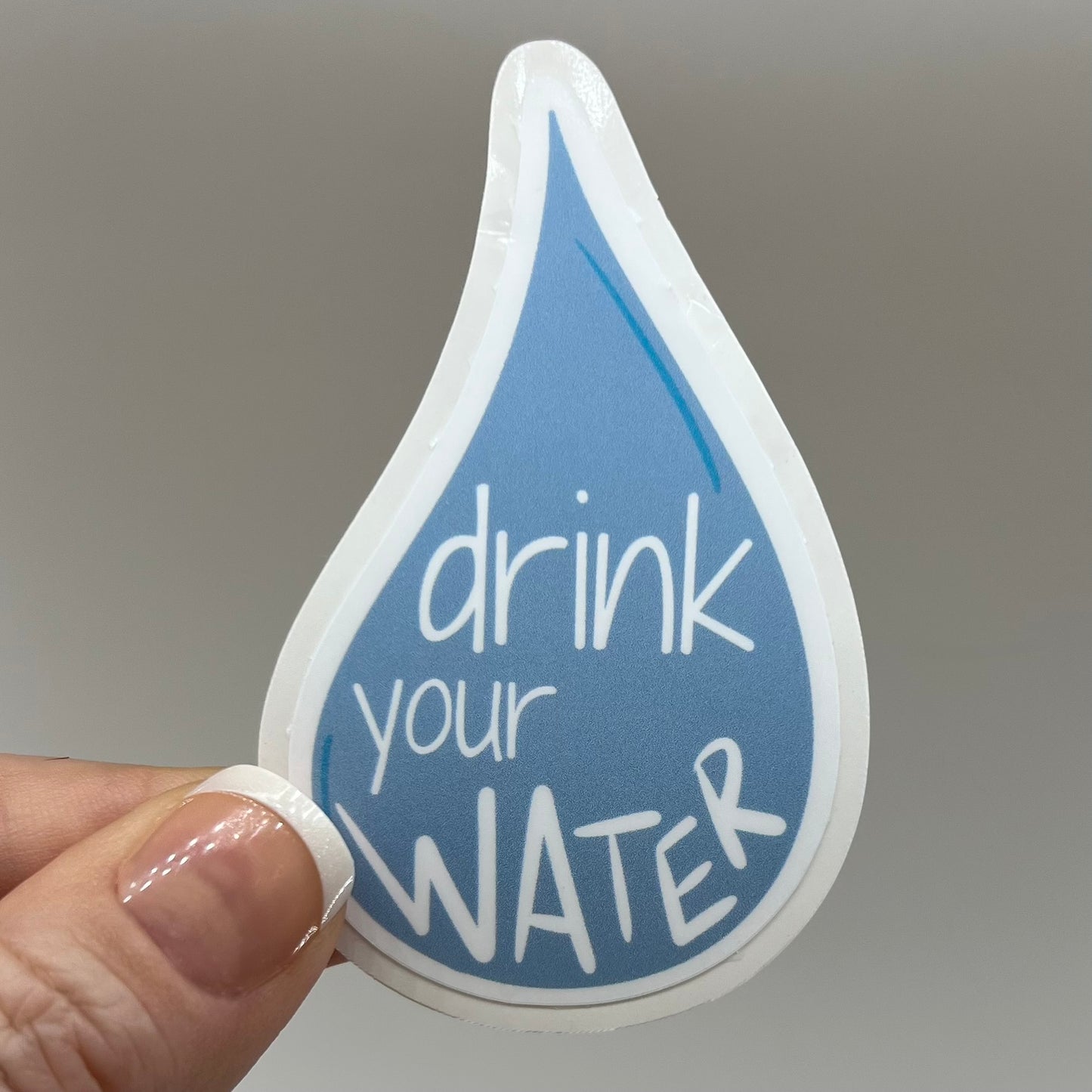A vinyl sticker with a blue water drop shape and the phrase 'drink your WATER' written in white.