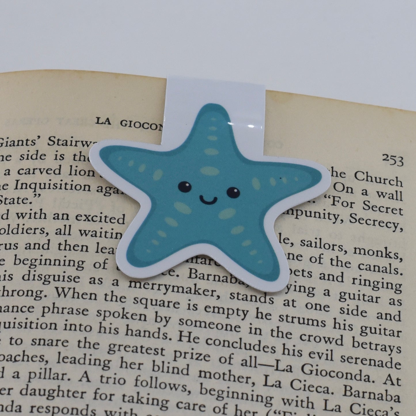 A glossy, magnetic bookmark shaped like a teal blue starfish with a happy kawaii face.