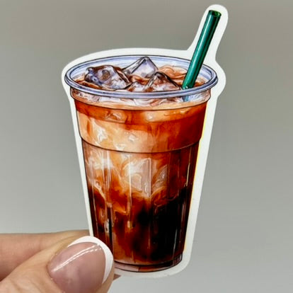 A vinyl sticker of an iced coffee cup. The sticker depicts a clear cup, green straw, and coffee and milk colored beverage inside.