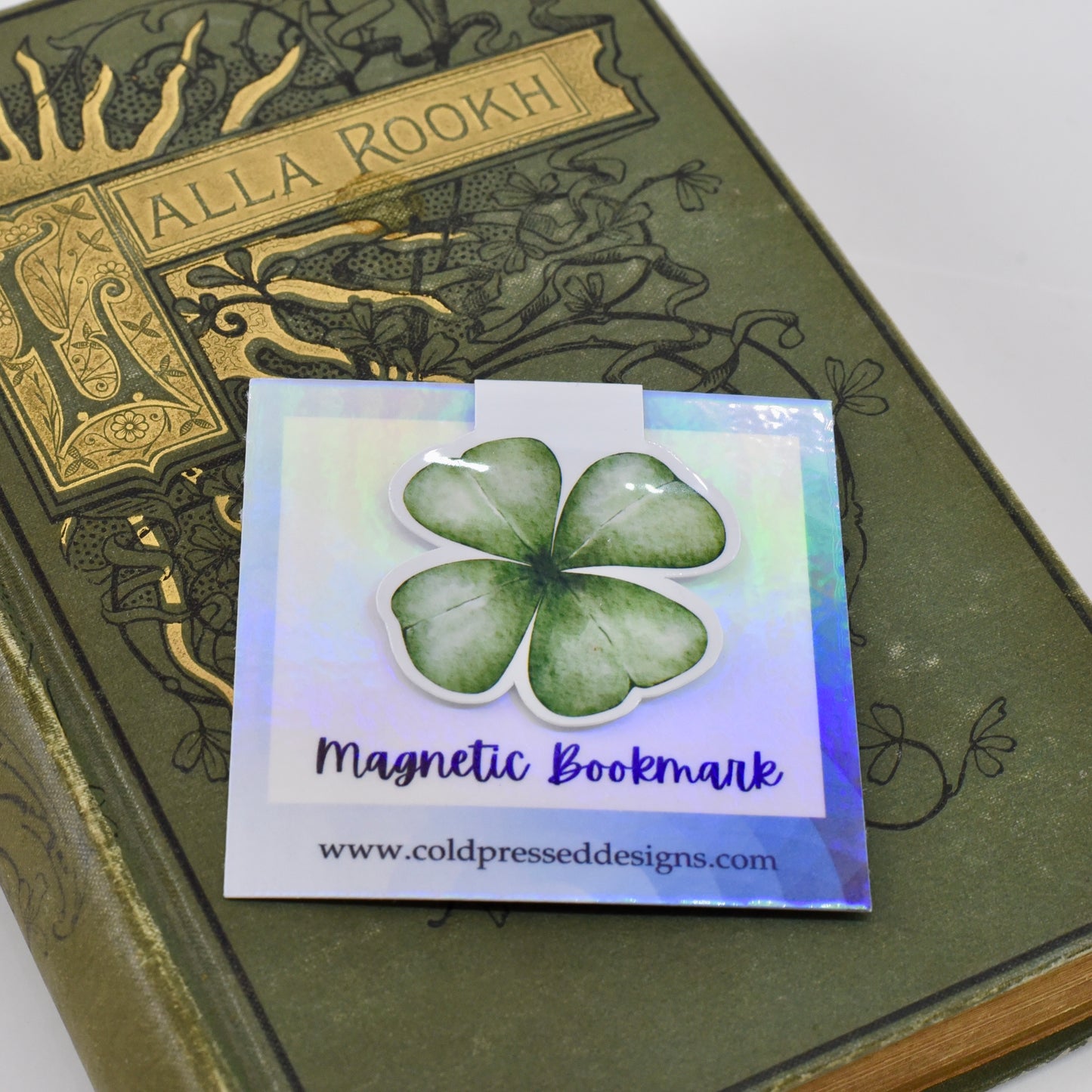 A glossy, green-colored magnetic bookmark in the shape of a four leaf clover.