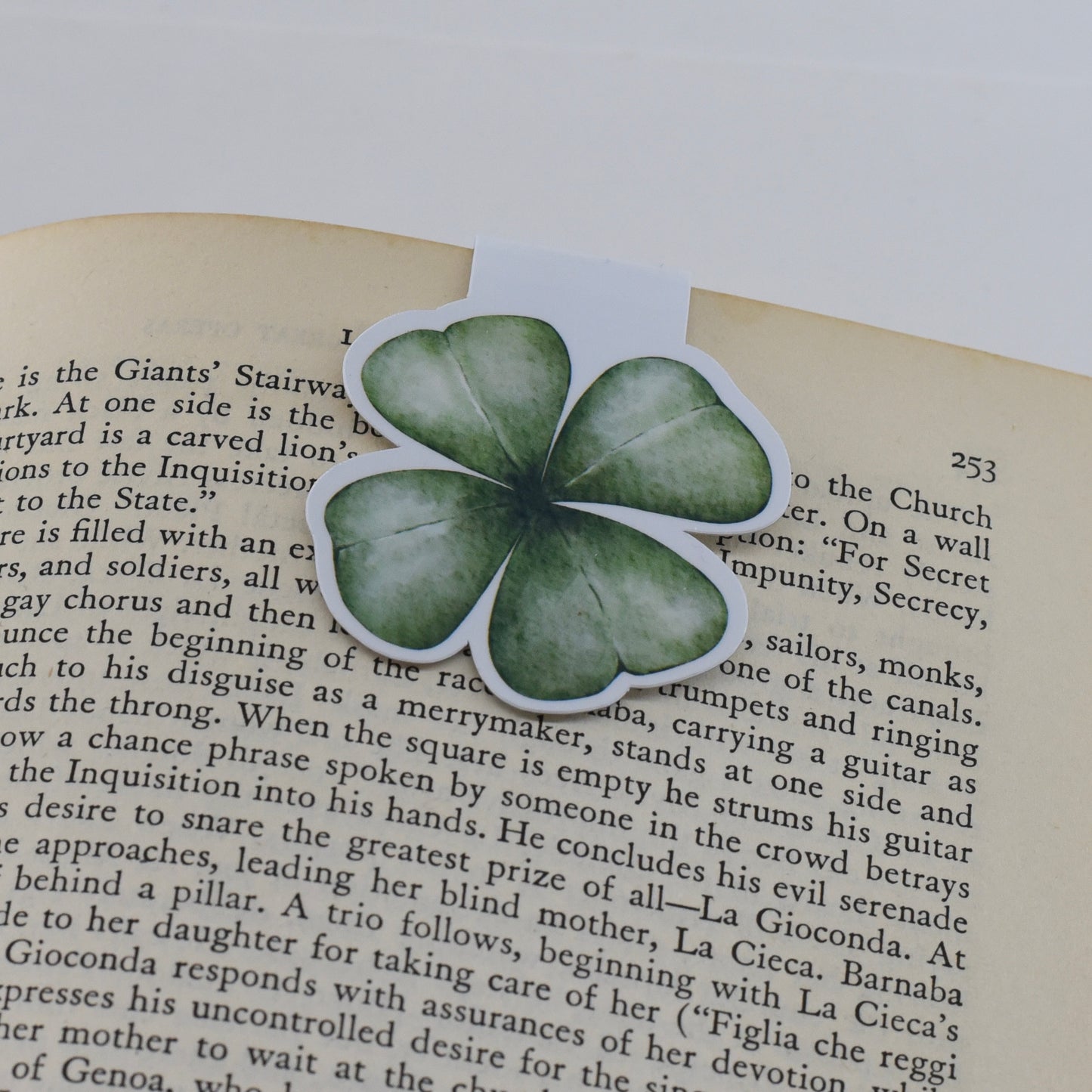 A glossy, green-colored magnetic bookmark in the shape of a four leaf clover.