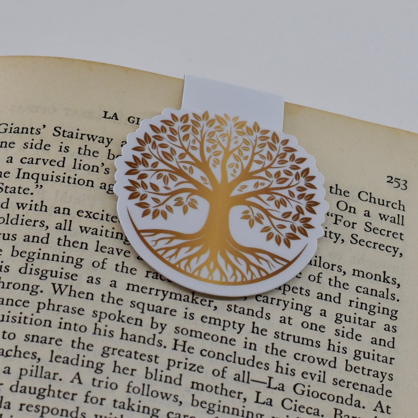 A round, glossy magnetic bookmark with a gold tree of life design.