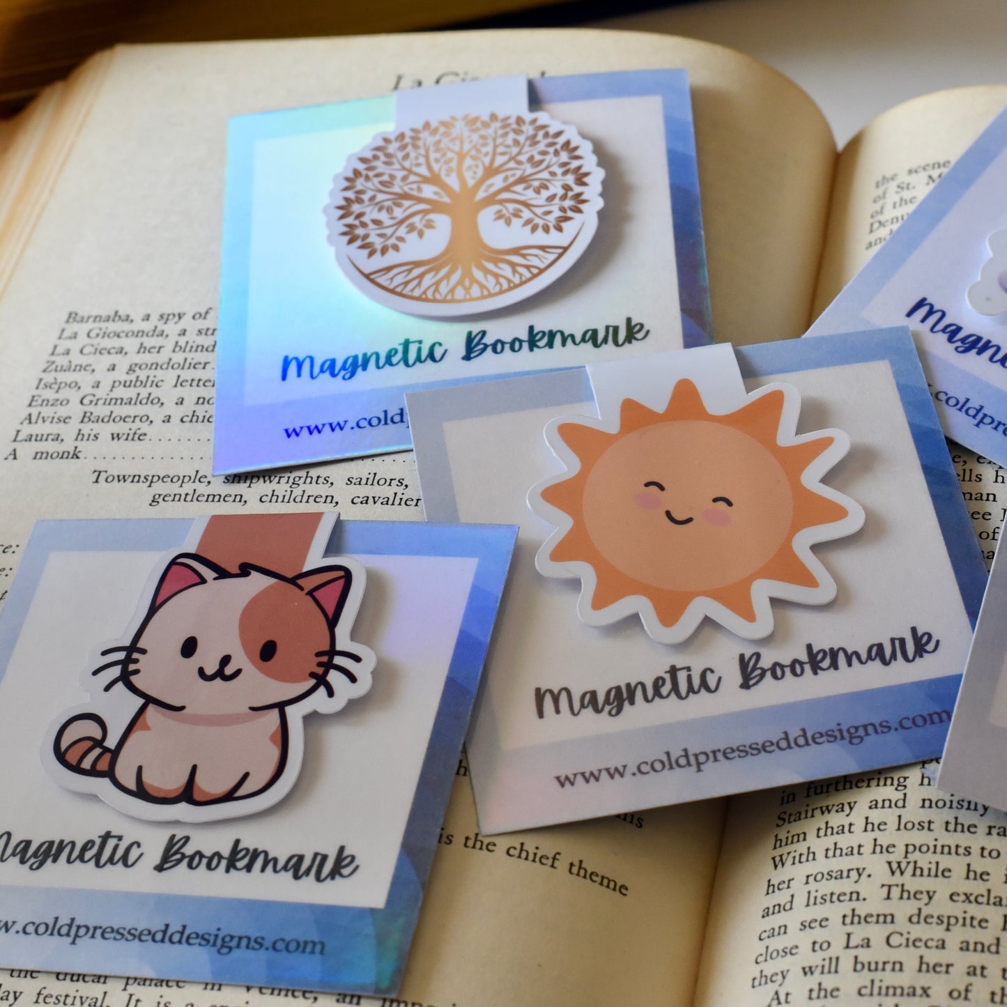 A group of magnetic bookmarks including a gold tree of life, a yellow smiling sun and a tan smiling kitten.