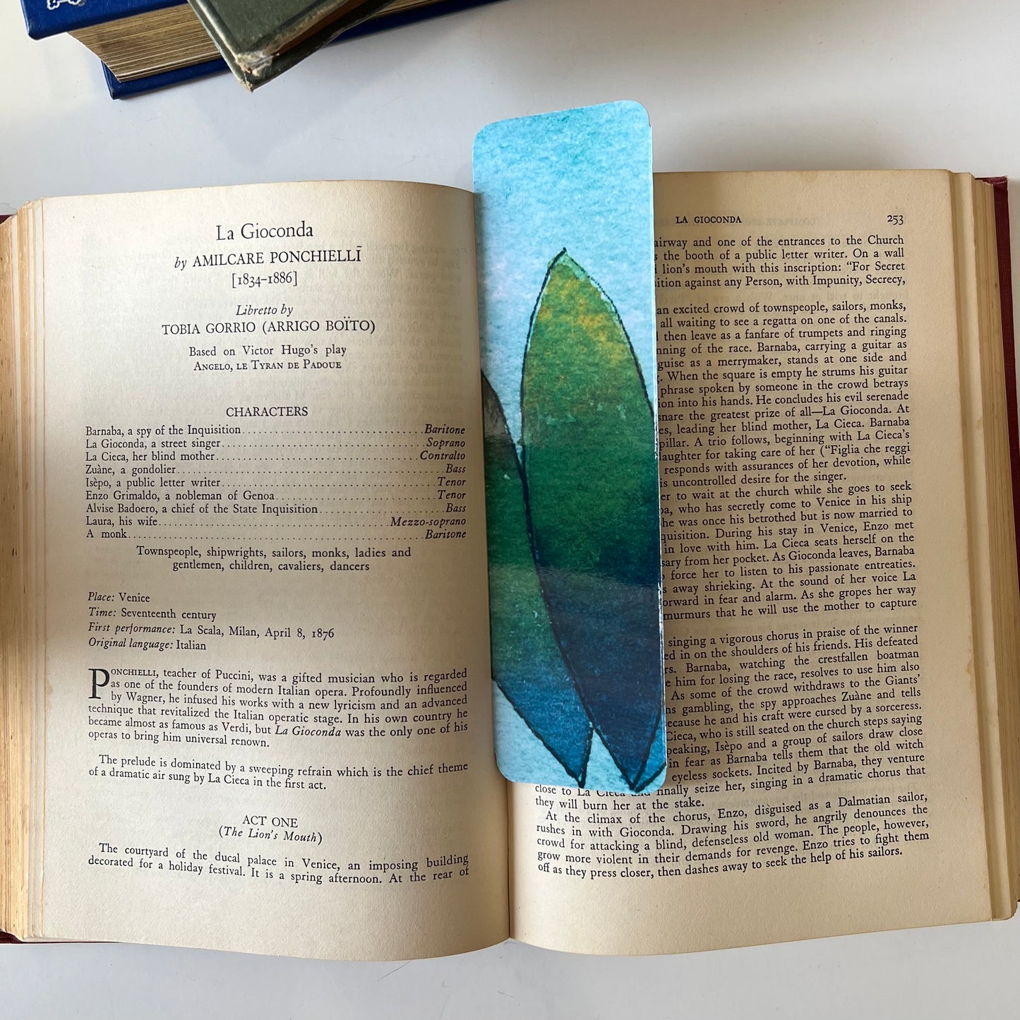 A glossy handmade bookmark with a watercolor floral doodle in blue and green.