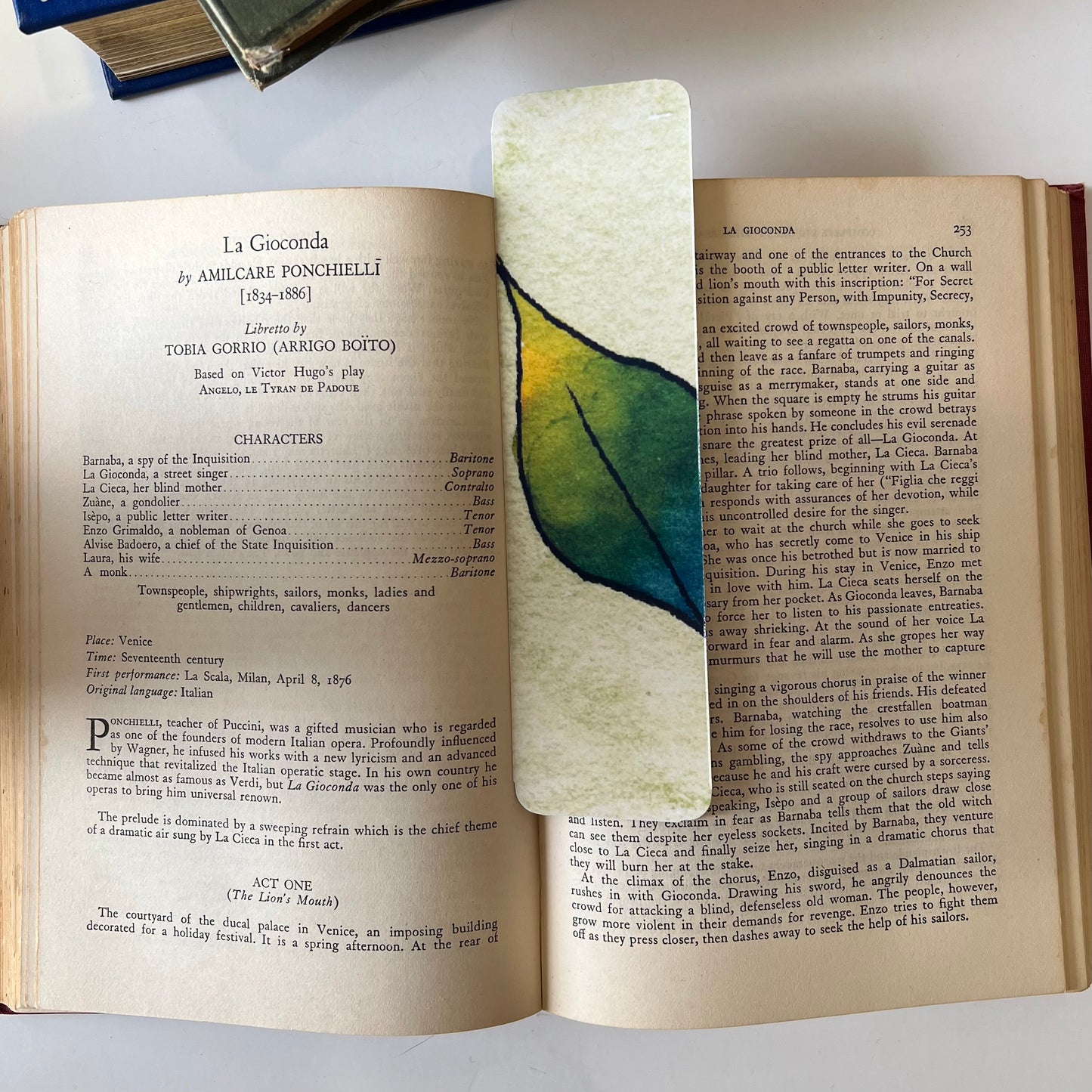 A glossy handmade bookmark with a watercolor floral doodle in blue, green and yellow.