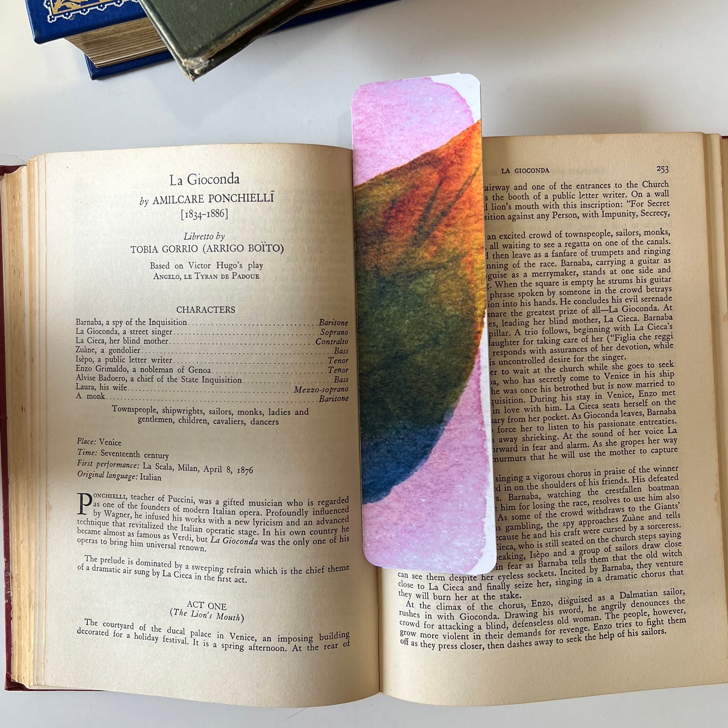 A glossy handmade bookmark with a watercolor floral doodle in pink, blue and orange.