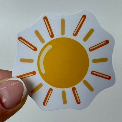 A vinyl sticker with a yellow sunshine design with a smooth glossy finish.