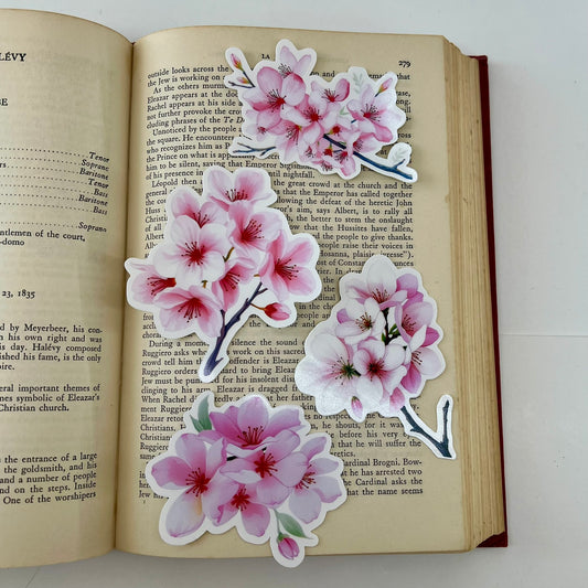 Stickers of pink cherry blossoms placed on an open book.