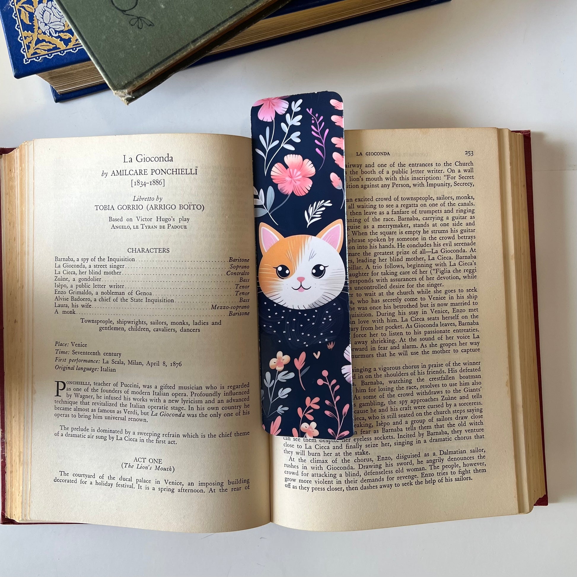 A handmade rectangular glossy bookmark with cute cat faces and floral patterns on a navy background.
