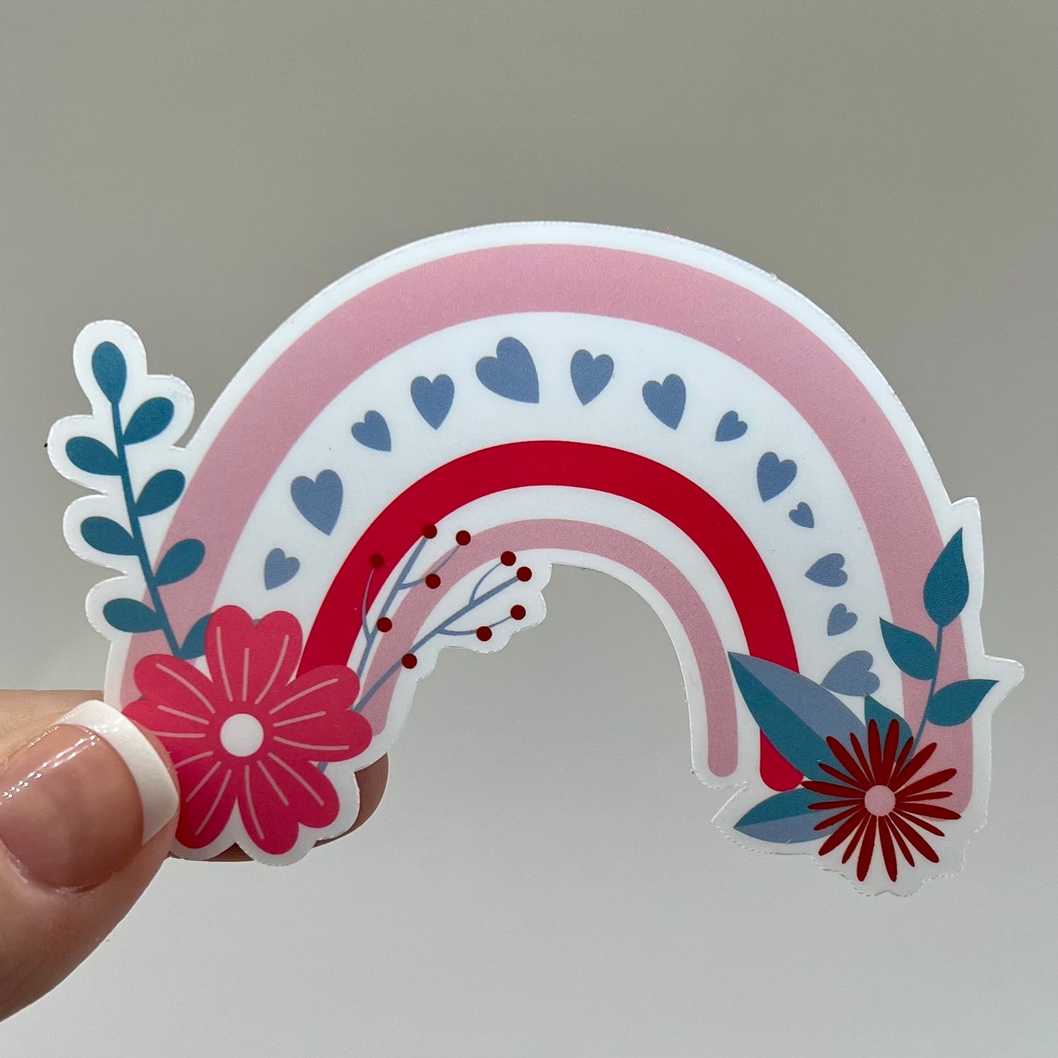 Vinyl sticker of a rainbow decorated with flowers and hearts.