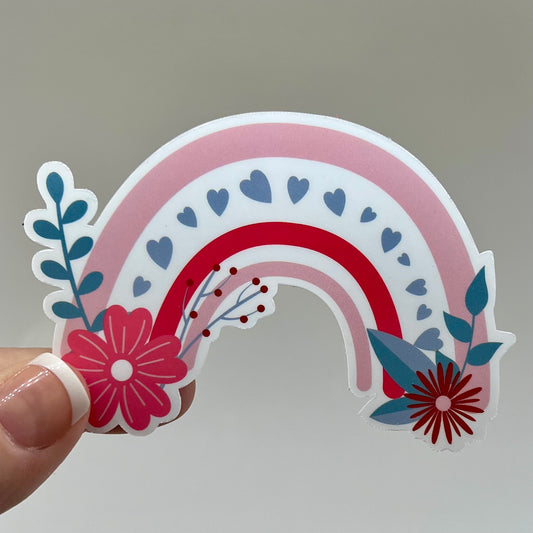 Vinyl sticker of a rainbow decorated with flowers and hearts.