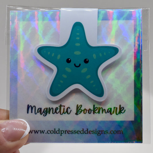 A glossy, magnetic bookmark shaped like a teal blue starfish with a happy kawaii face.