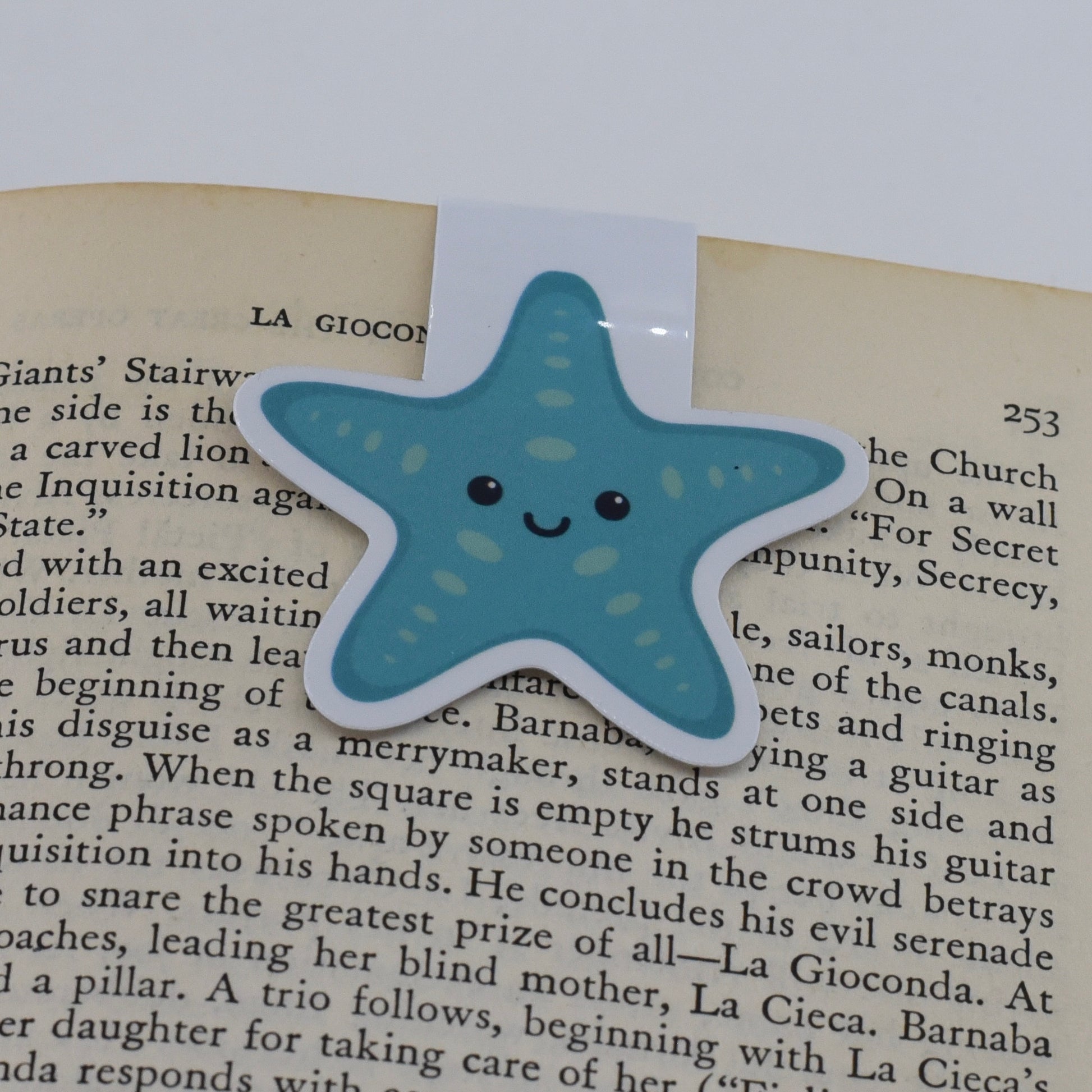 A glossy, magnetic bookmark shaped like a teal blue starfish with a happy kawaii face.