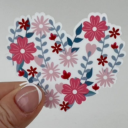 A vinyl sticker with a heart-shaped design, featuring a variety of spring flowers in shades of pink, white, and red.