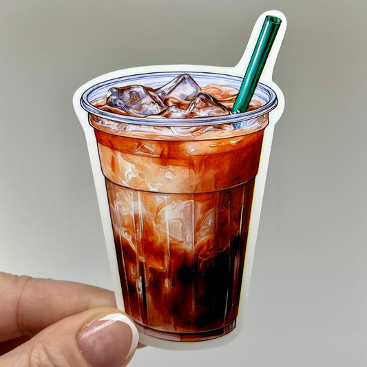 A vinyl sticker of an iced coffee cup. The sticker depicts a clear cup, green straw, and coffee and milk colored beverage inside.