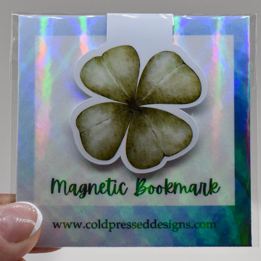 A glossy, green-colored magnetic bookmark in the shape of a four leaf clover.