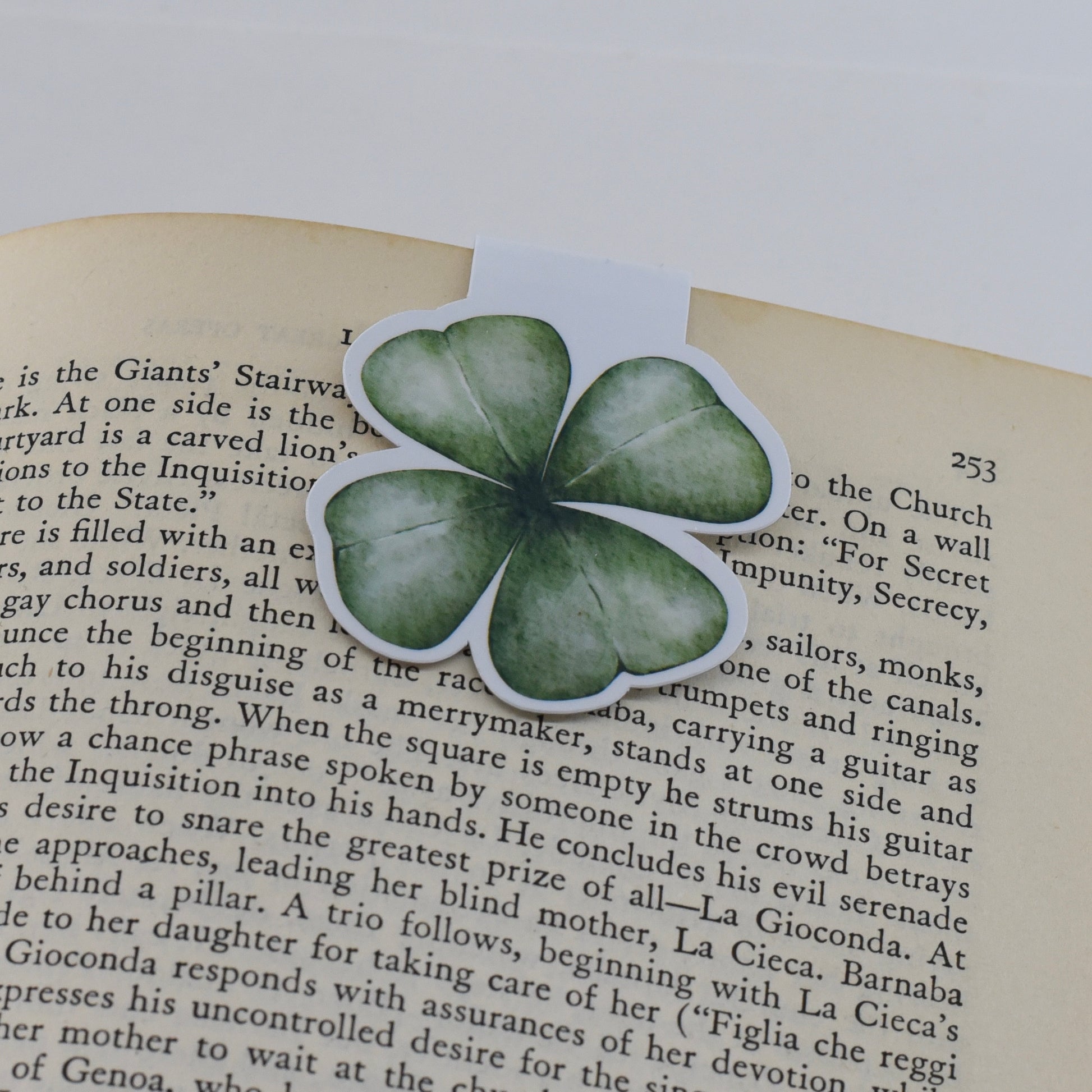 A glossy, green-colored magnetic bookmark in the shape of a four leaf clover.