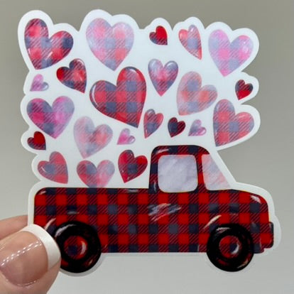 A vinyl sticker of a red pickup truck with a plaid pattern and hearts design.