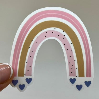 A vinyl sticker depicting a pink rainbow with hearts at the ends of the arch and dots along the rainbow.