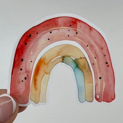 A vinyl sticker with a red, yellow and blue watercolor rainbow design.
