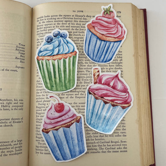 Four vinyl stickers with illustrations of cupcakes in blue, pink, and green colors, garnished with blueberries, strawberry, cherry and pirouette.