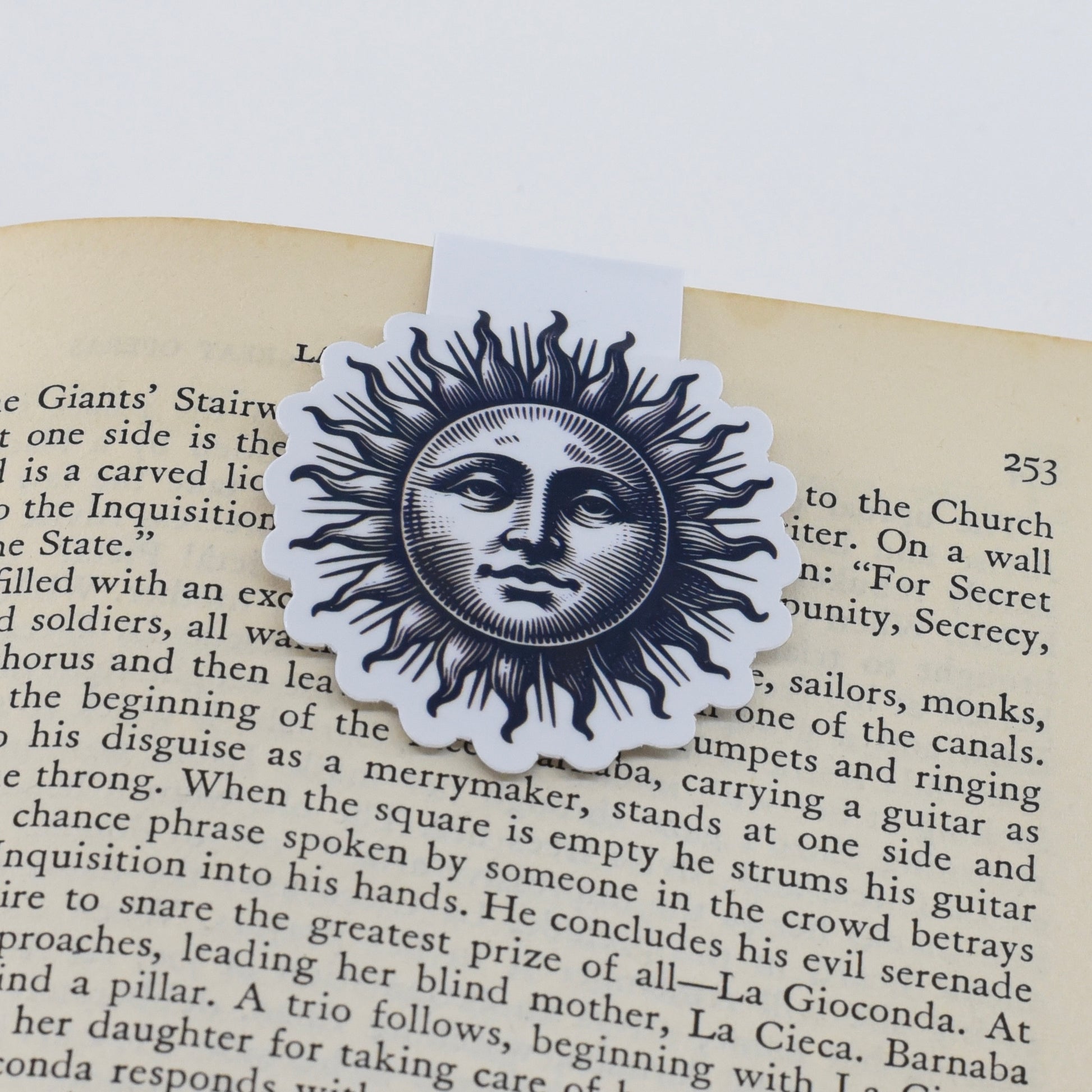 A magnetic bookmark with a black decorative sun with a realistic face.