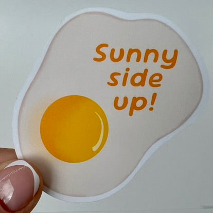 A vinyl sticker with an illustration of a fried egg and the text 'Sunny side up!' 