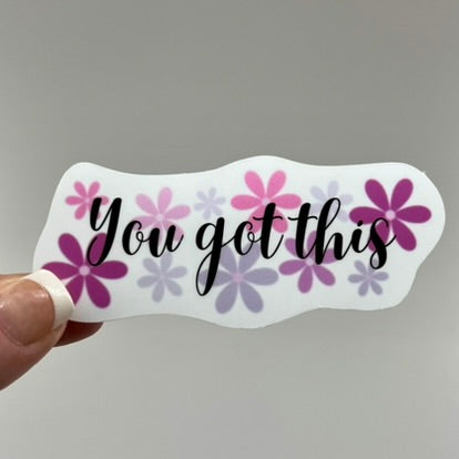 A vinyl sticker with the phrase 'You got this' written in black ink, surrounded by a pattern of pink and purple flowers.